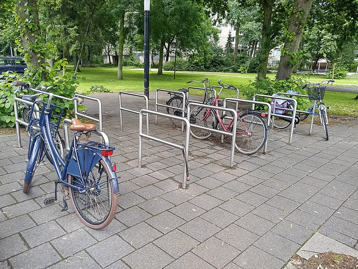 Rij metalen fietsbeugels in een park met geparkeerde fietsen